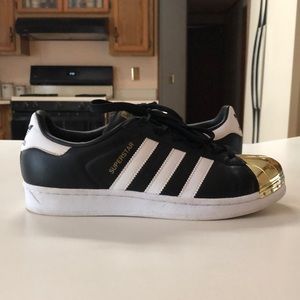 Adidas Superstars with gold toe.